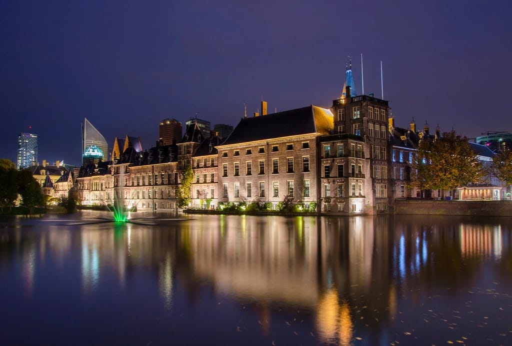 Prédio histórico iluminado à noite, refletido na água de um canal