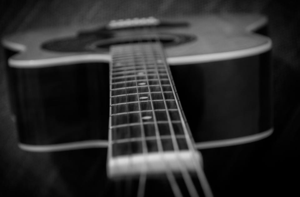 Braço de um violão em preto e branco, com as cordas em foco