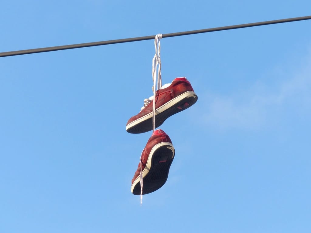 Par de tênis vermelhos pendurado em um fio, contra o céu azul