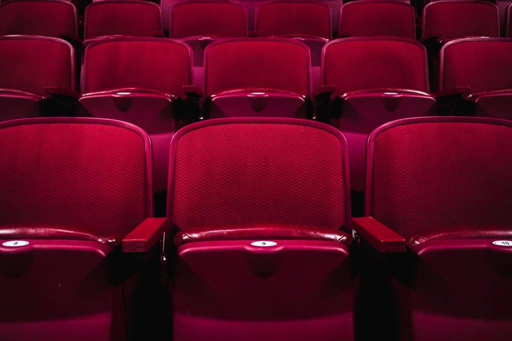 Fileiras de poltronas vermelhas vazias em uma sala de cinema