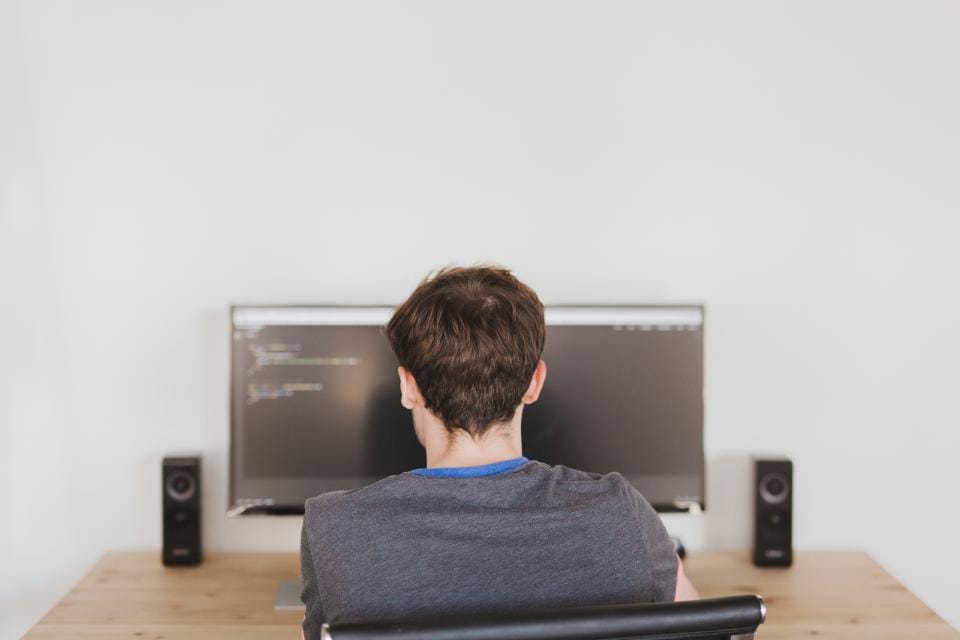 Pessoa de costas diante de um monitor ultralargo em uma sala escura